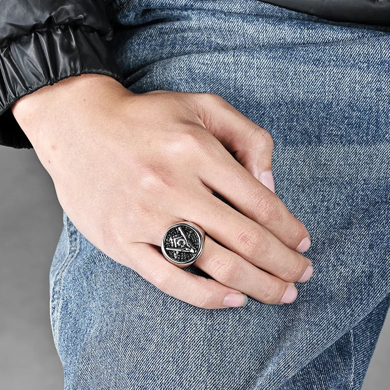 Silver-tone round Masonic ring worn beside denim