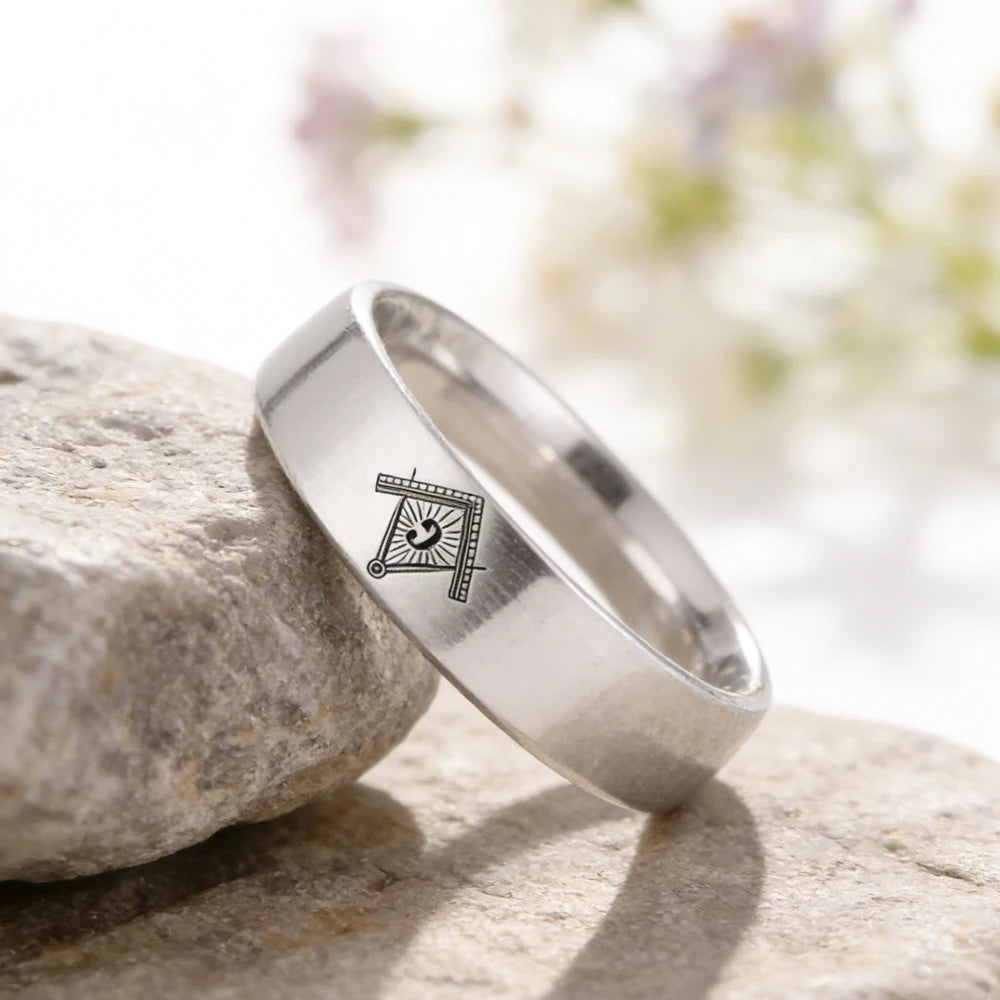 Silver-tone engraved Masonic band leaning against stone