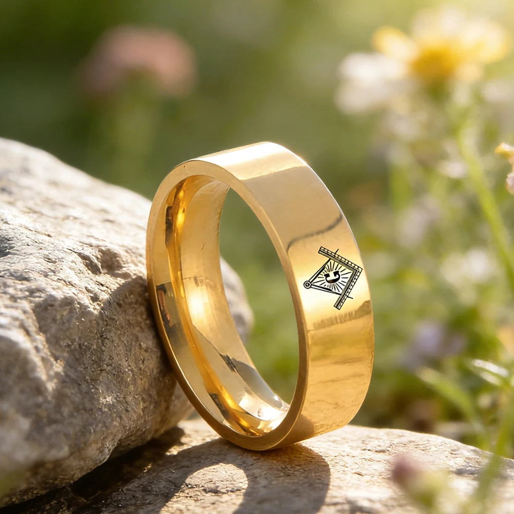 Gold-tone engraved Masonic band beside stone