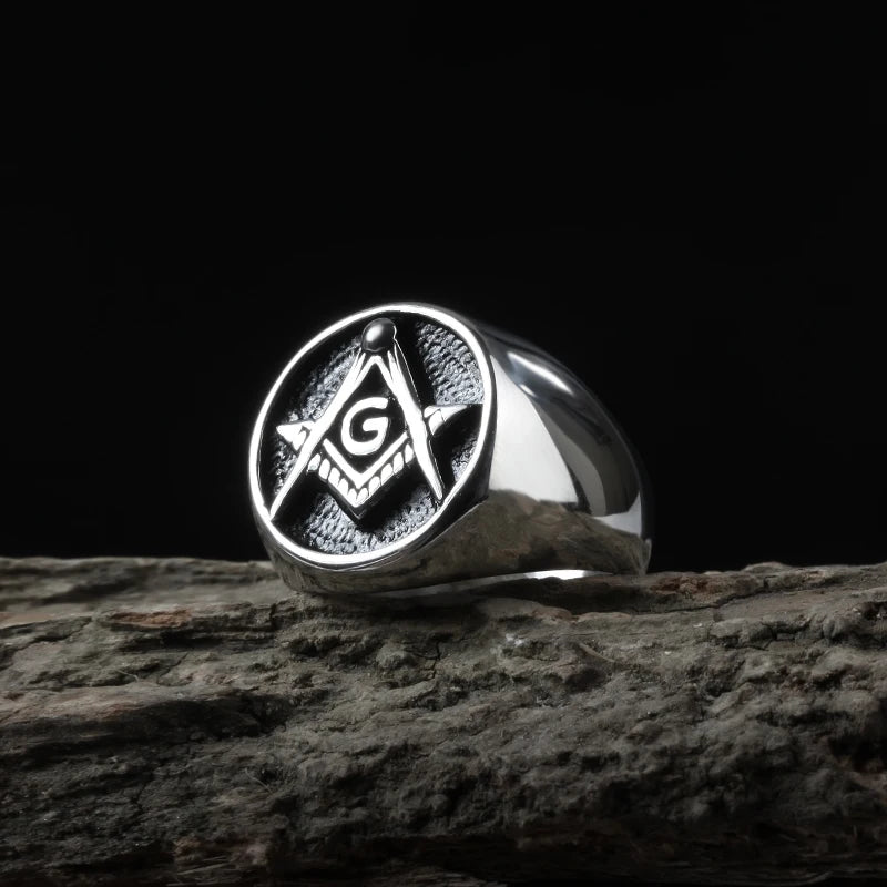 Round black-face Masonic ring displayed on textured wood