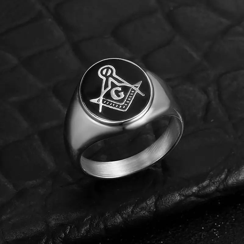 Silver-tone black medallion Masonic ring on dark textured surface